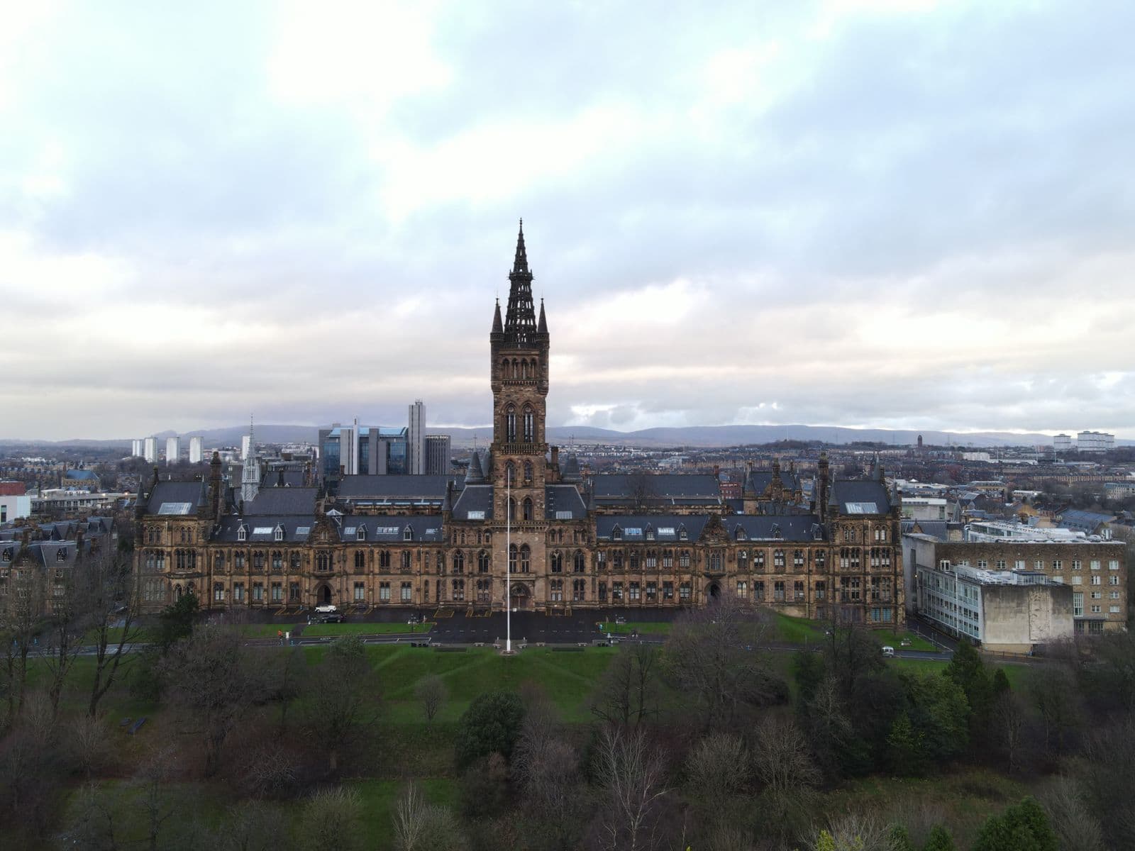 An aerial view of a grand Gothic university building and its grounds