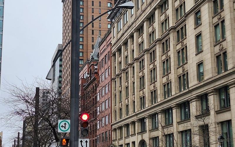 A downtown Montreal street lined with stone office buildings on an overcast day